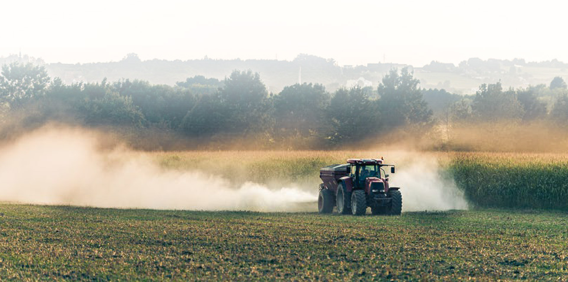 Ciągnik na polu rozsypujący wapno